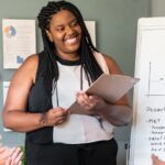 Woman smiles at her team while giving a presentation with a chart behind her